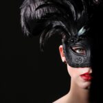 Eine Frau mit einer aufwendigen schwarzen Maske und roten Lippen, teilweise im Schatten, was eine geheimnisvolle und verführerische Stimmung erzeugt.