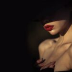 Detailaufnahme einer stilvollen Frau mit rotem Lippenstift und einem Schatteneffekt, passend zum Thema Escort werden.